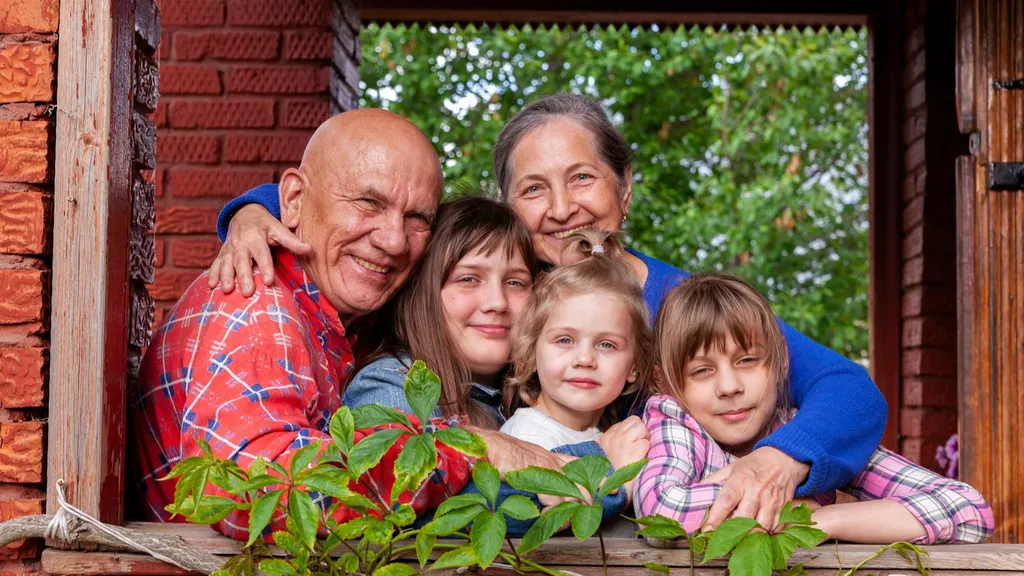 Grands-parents et petits-enfants souriants à la fenêtre de leur maison
